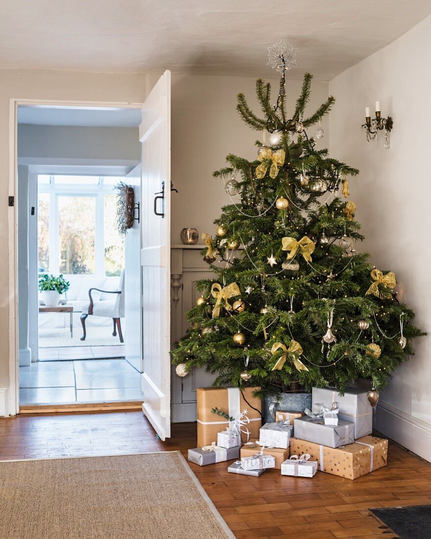 Presents wrapped in grey and brown under Christmas tree in hallway