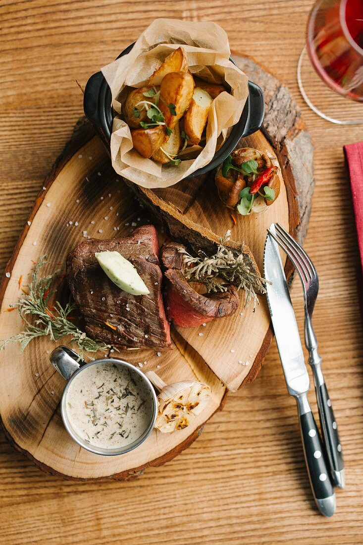 Steak mit Ofenkartoffeln und Pilzsauce serviert auf Baumscheibe