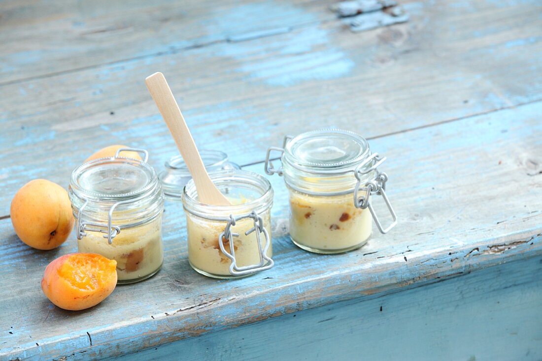 Apricot and quark pancakes baked in glass jars on a blue wooden table