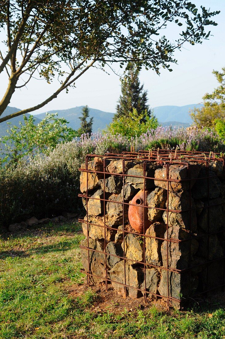 Kunstwerk aus Steinen in einem Metallgitter im mediterranen Garten