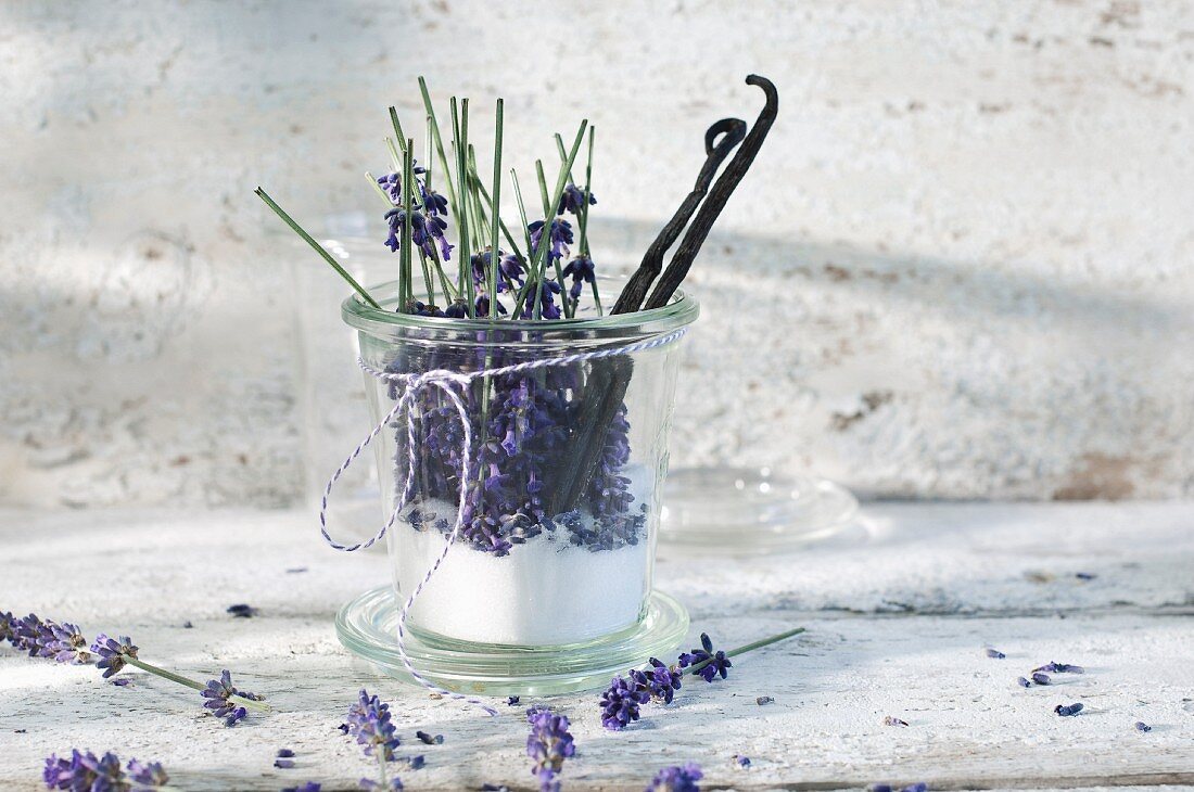Glass of lavender sugar with avender blossoms and vanilla beans