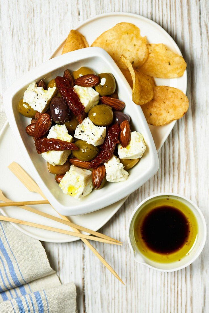 Feta with pickled olives, dried tomatoes, potato chips and olive oil