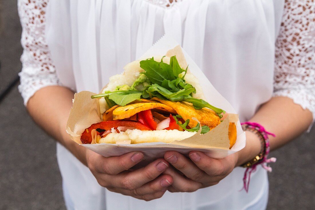 Hands of teenage girl holding corn flat bread stuffed with vegetables