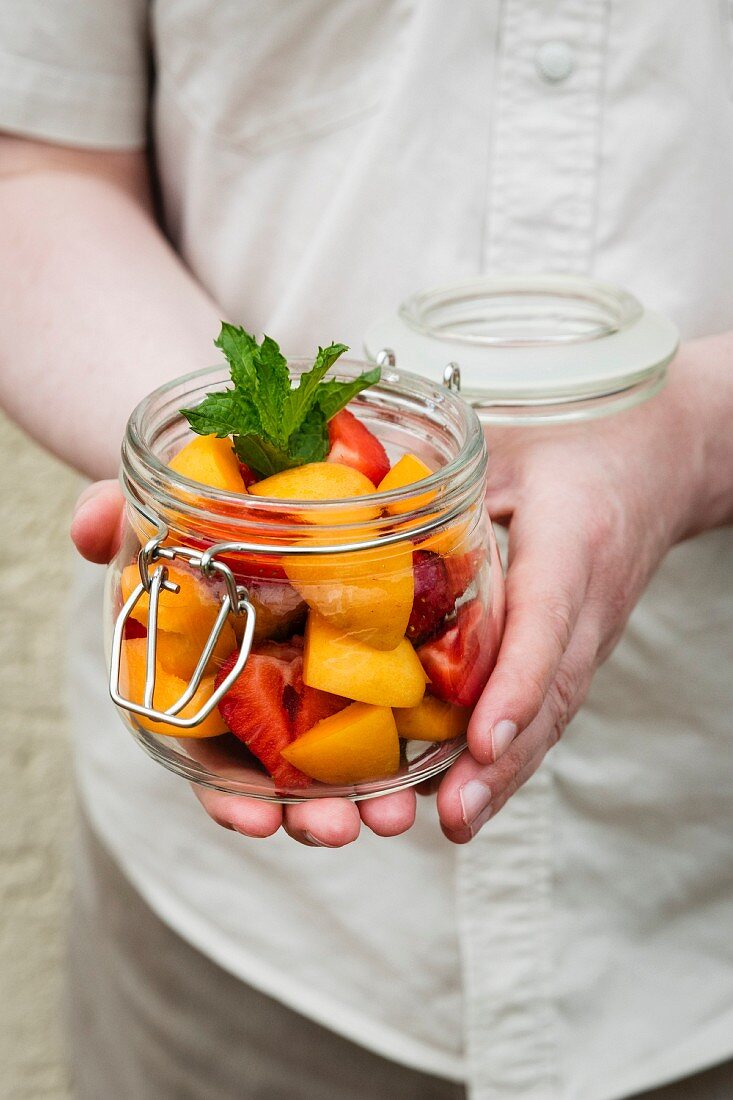 Person holding jar with fruit salad