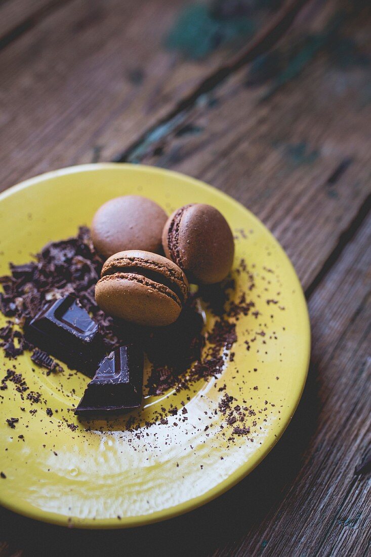 Macarons und Schokoladenraspel auf gelbem Teller