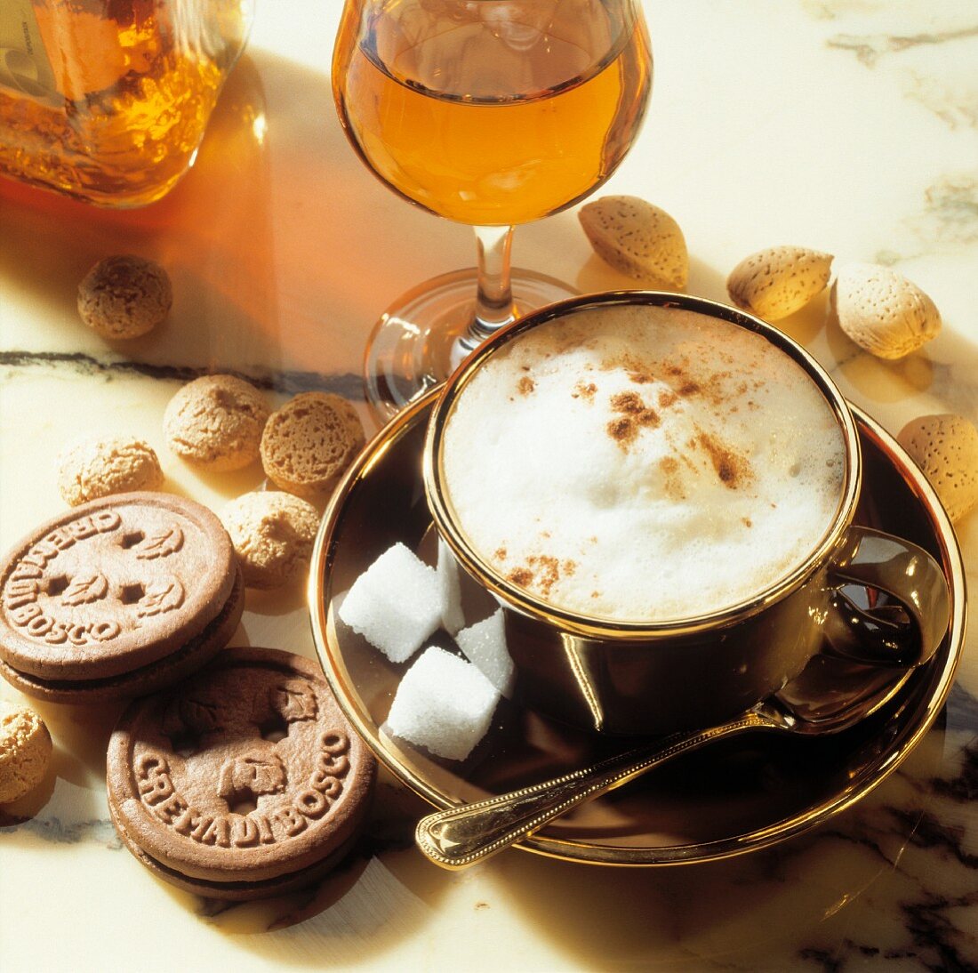 Eine Tasse Cappuccino mit Zuckerwürfeln, Keksen & Amarettini