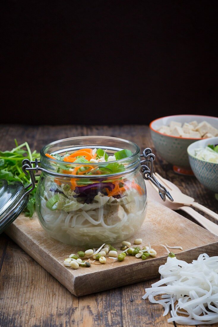 Asian rice noodle soup with vegetables and tofu in jar