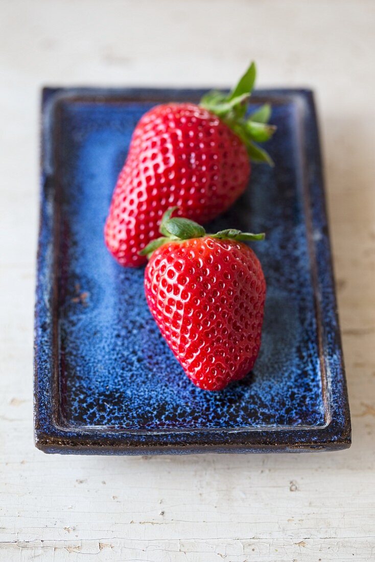 Zwei Erdbeeren auf blauem Teller