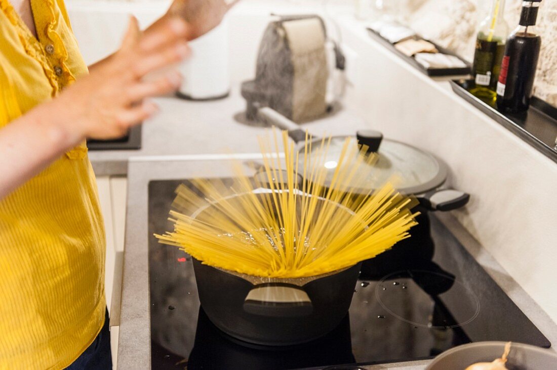 Frau in der Küche bereitet Spaghetti zu
