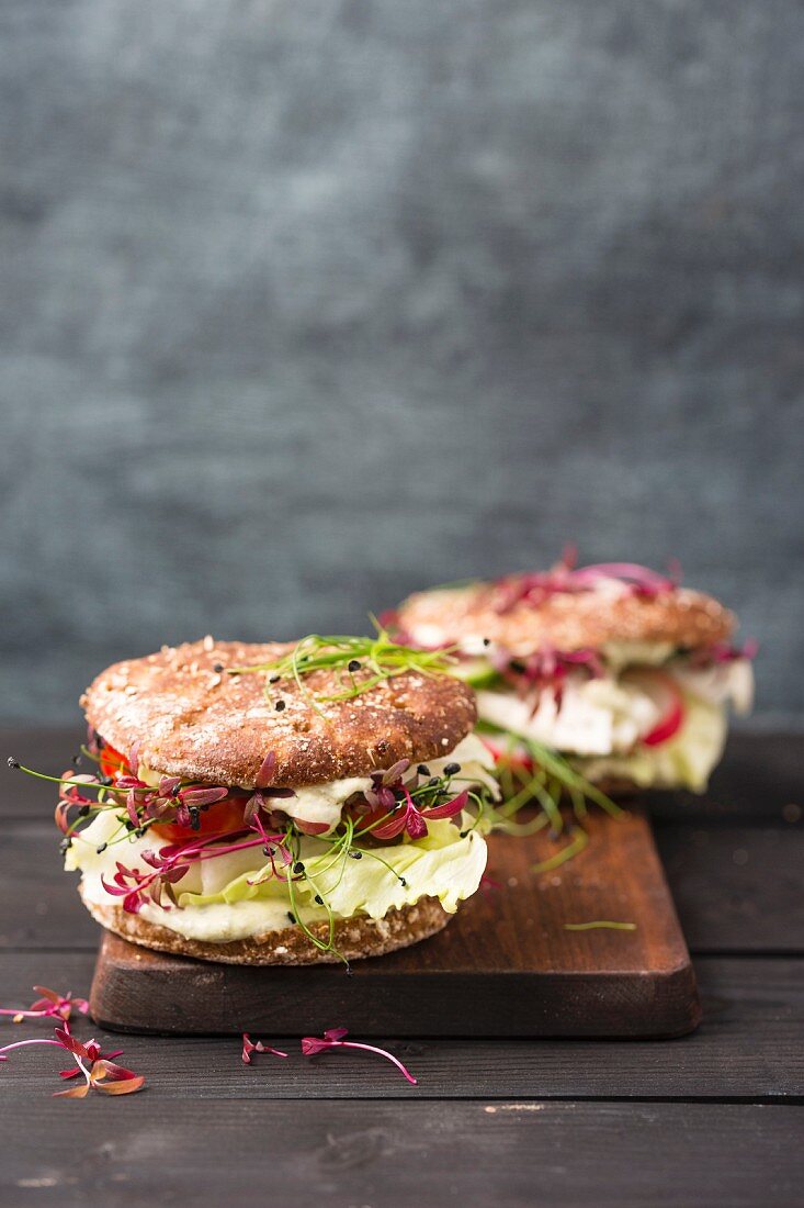 Veganer Vollkornburger mit Salat, Radieschen, Tomaten, Kresse, Schnittlauch und Joghurt-Kräutersosse