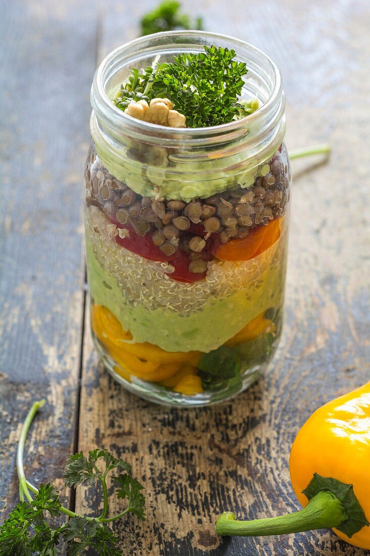 Salat mit Linsen, Quinoa, Avocado, Gemüse und Walnüssen im Glas