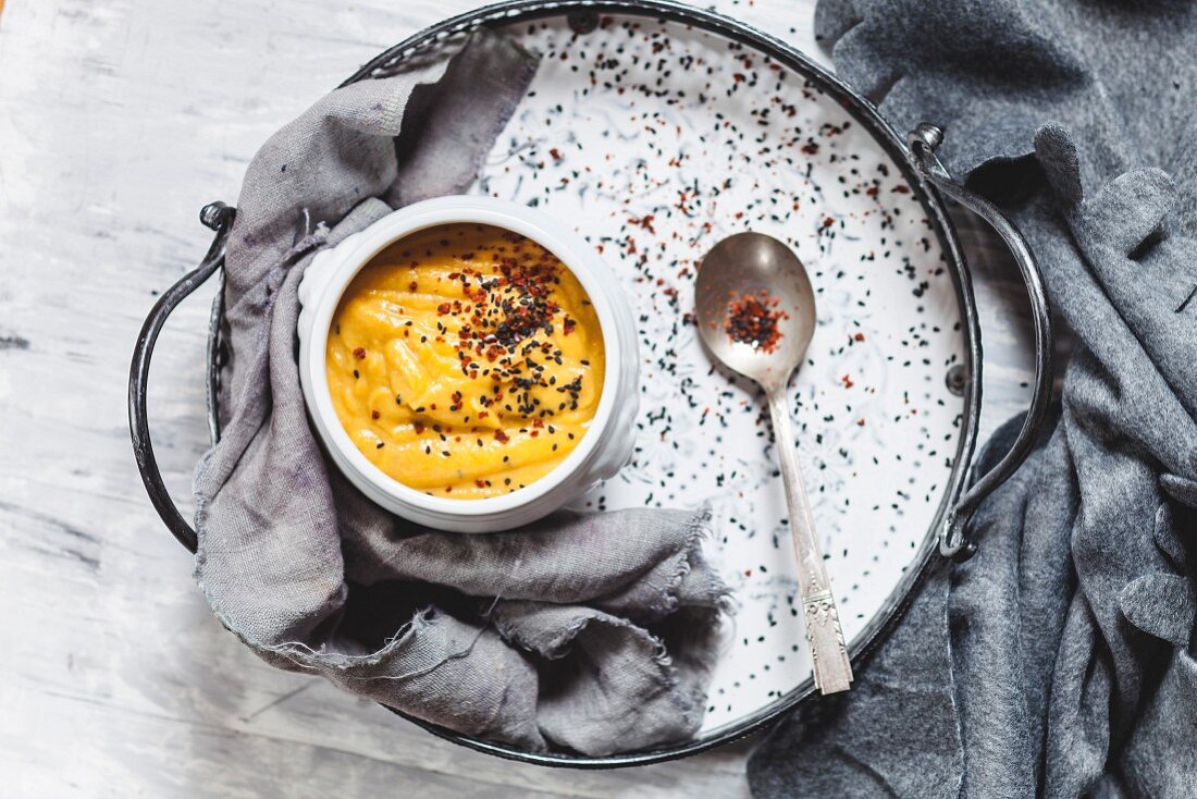 Pumpkin soup with black sesame and chili flakes on tray