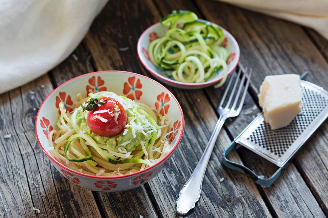 Spaghetti mit Zucchinispaghetti, Guacamole, Kirschtomate und geriebenem Parmesan