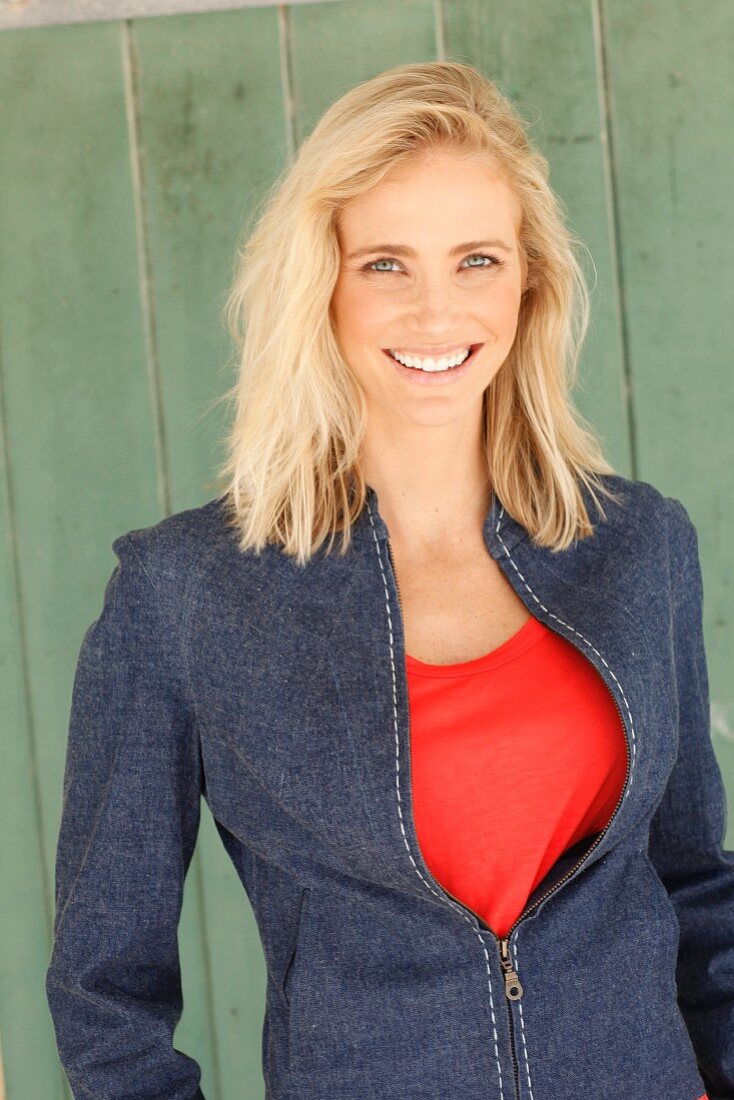 A blonde woman wearing a red top and a denim jacket