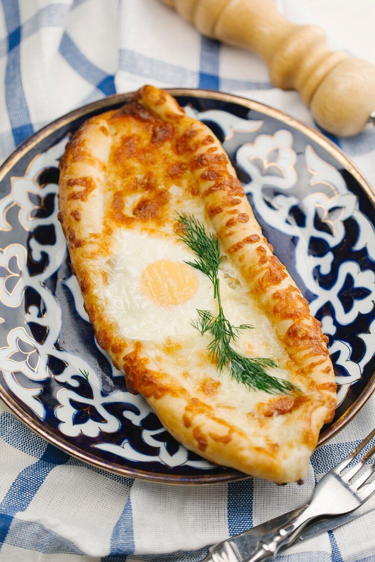 An oval-shaped flatbread pizza with a fried egg on the top