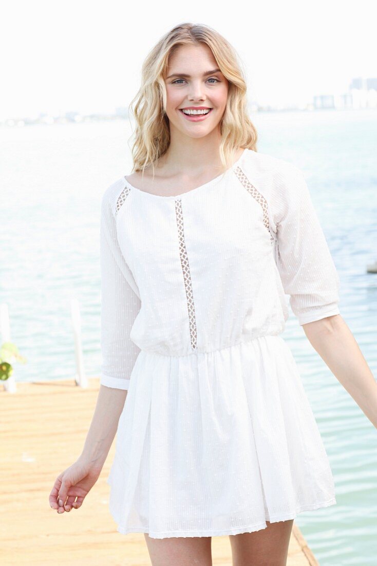 A blonde woman wearing a white summer dress with peekaboo design