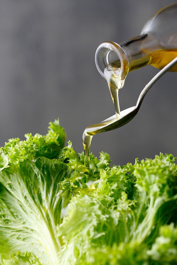Olivenöl über frischen Blattsalat gießen