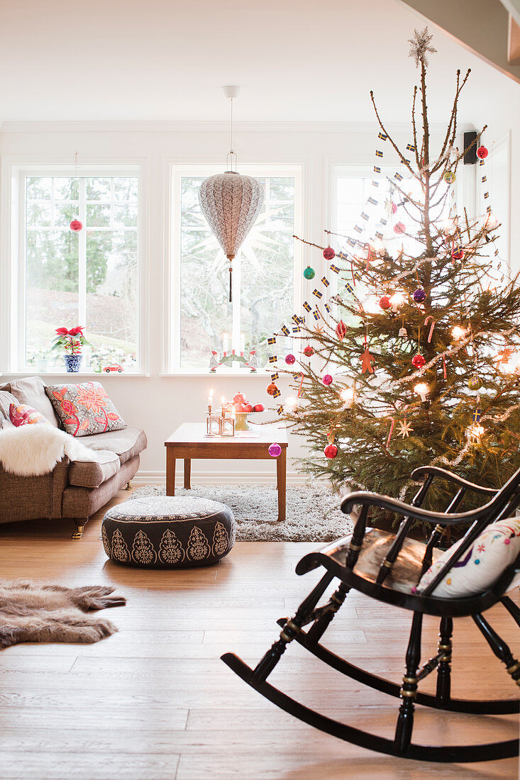 Schaukelstuhl vor geschmücktem Weihnachtsbaum im Wohnzimmer