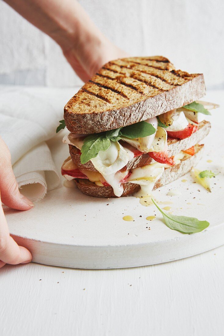 A grilled spelt bread sandwich with strawberries, Camembert and whisky shallots