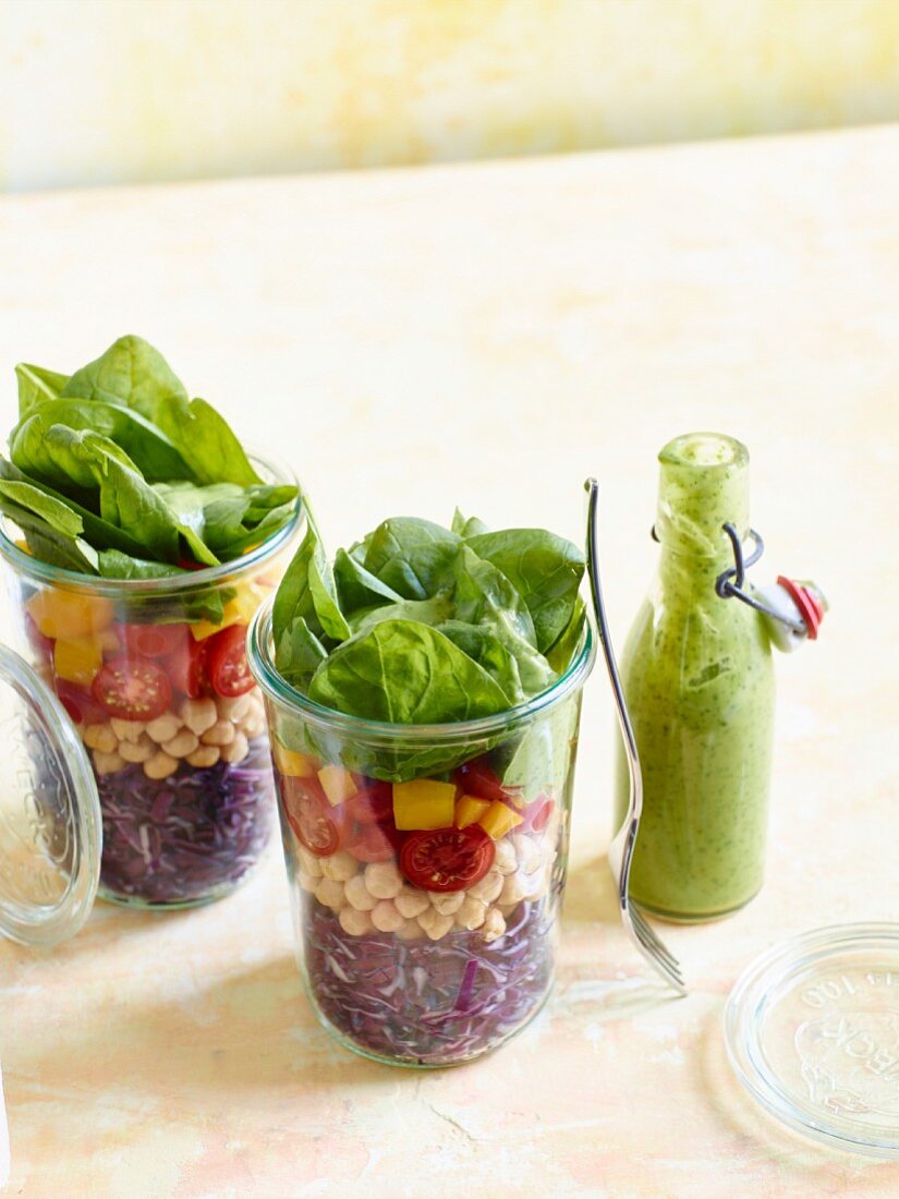 Brightly coloured layered salad in a glass with avocado dressing