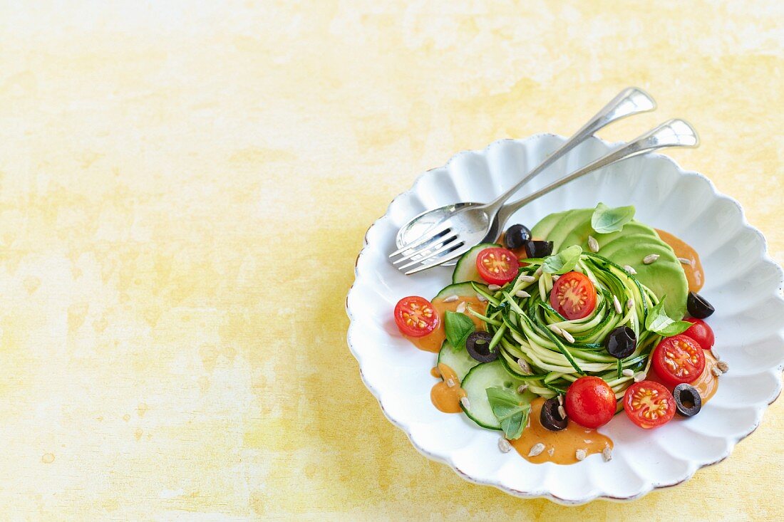 Vegan courgette pasta with avocado, olives and tomato sauce