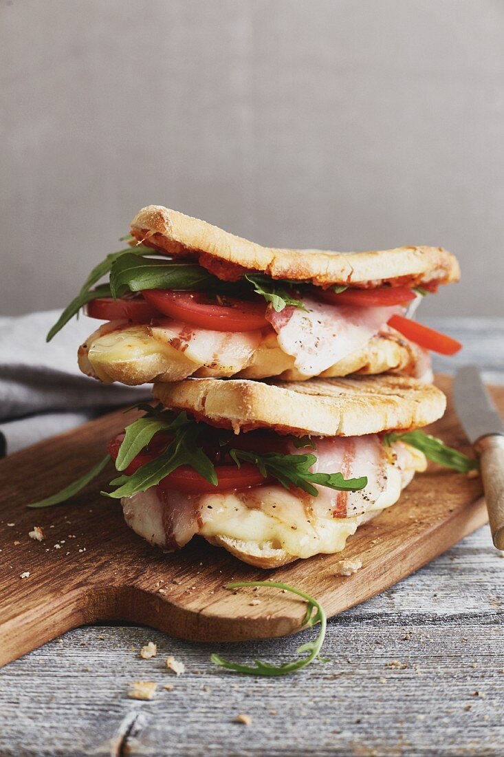 Panini-Sandwich 'Caprese' mit Tomaten, Rucola, Mozzarella und Pancetta