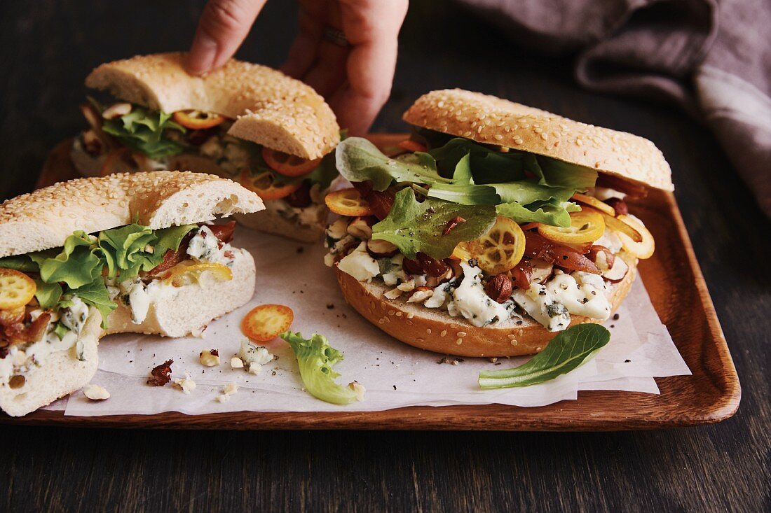 A sesame seed bagel with Roquefort cheese, hazelnuts and kumquats