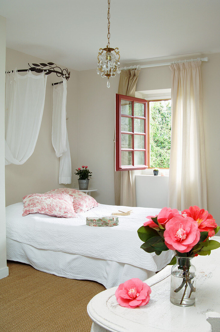 Vase of camellias in French-style bedroom