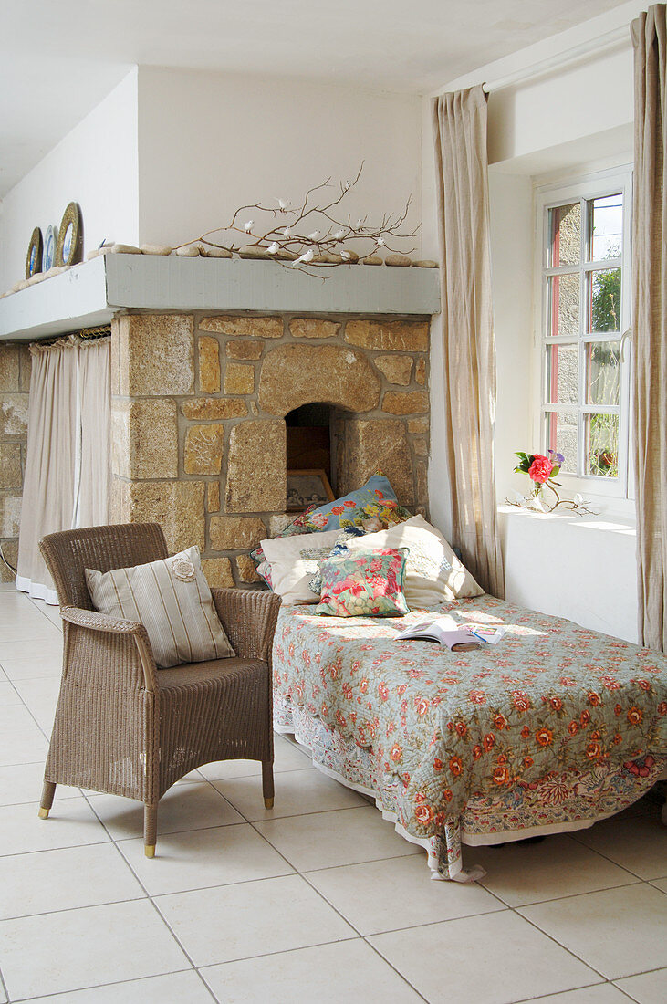 Armchair and couch in front of window and exposed stone wall