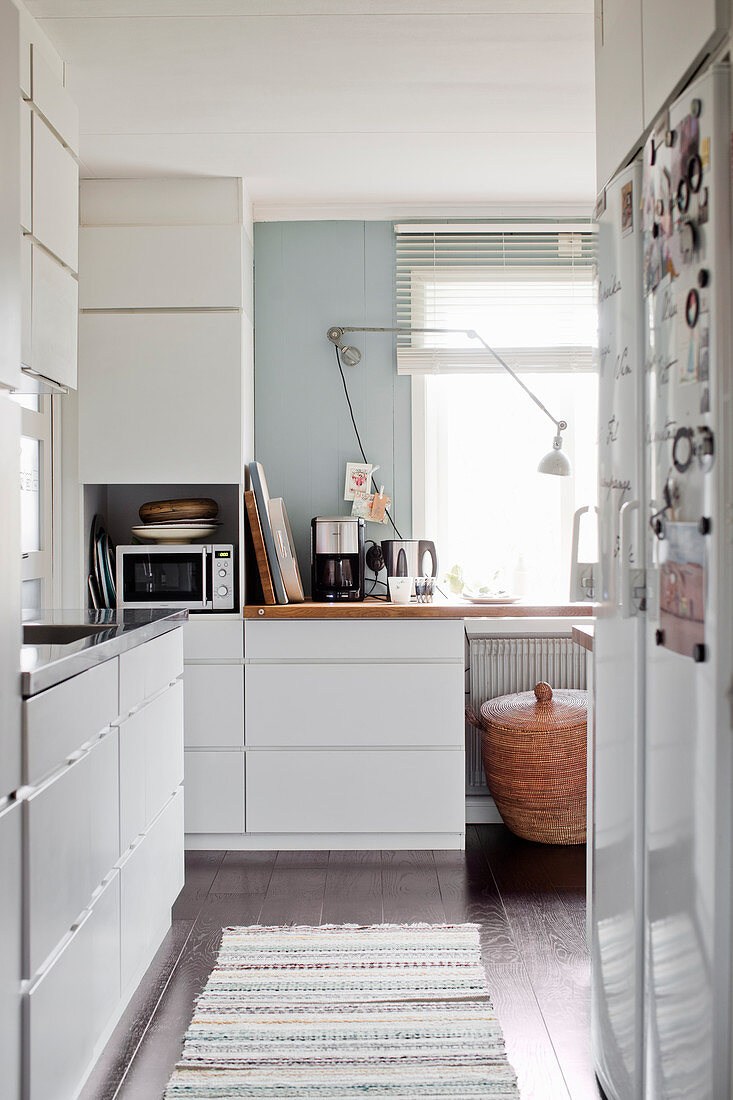 White fitted kitchen with window and dark wooden floor