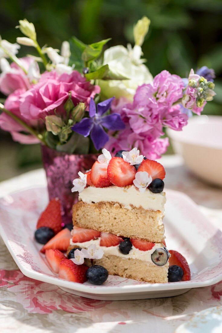 Ein Stück Victoria Sponge Cake mit Beeren auf Tisch im Freien