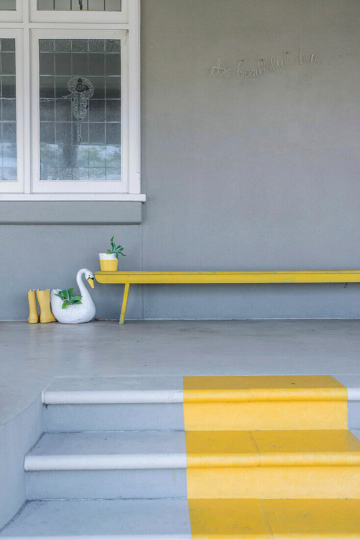 Grey staircase with yellow stripes, yellow boots and swan flower pot