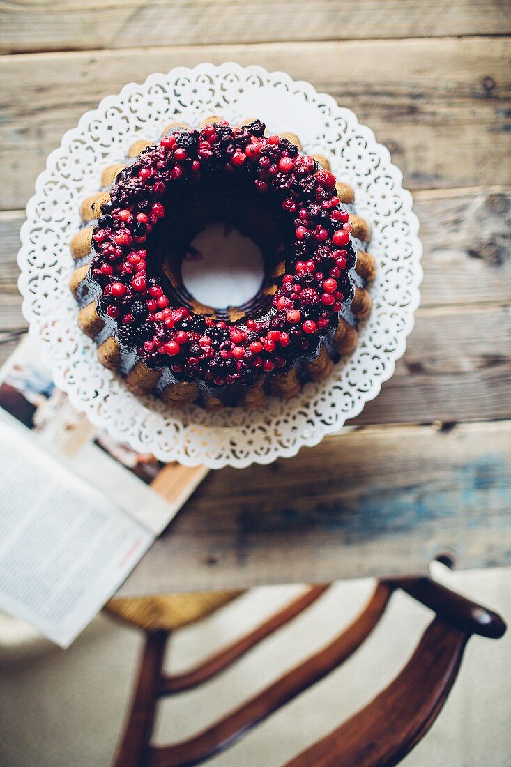 A ring-shaped Bundt cake with berries and chocolate glazing