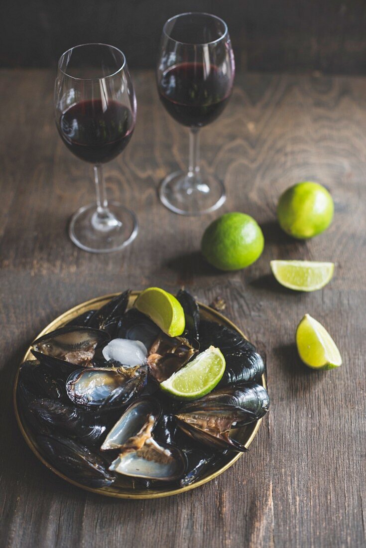 Cooked mussels served with lime wedges and red wine