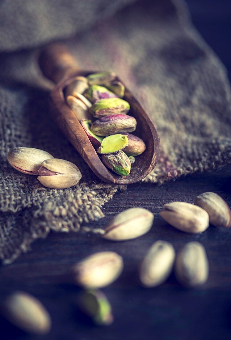 An arrangement of pistachios on a wooden scoop