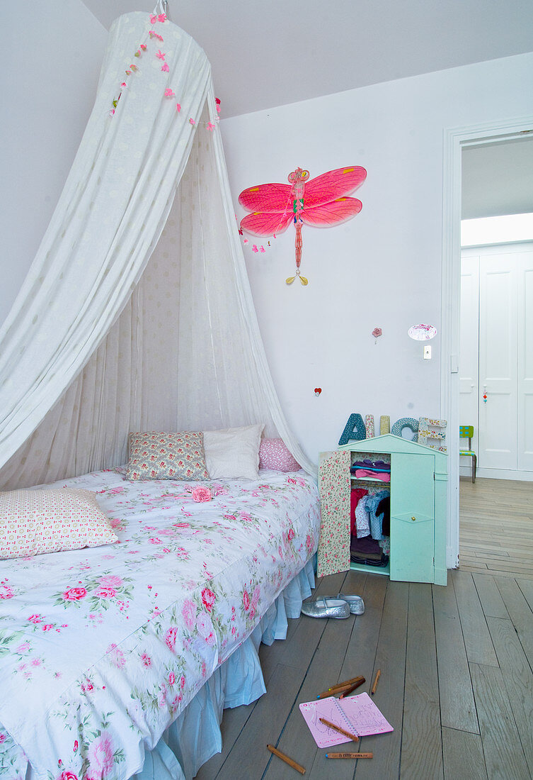 Canopied bed with floral bedlinen in girl's bedroom