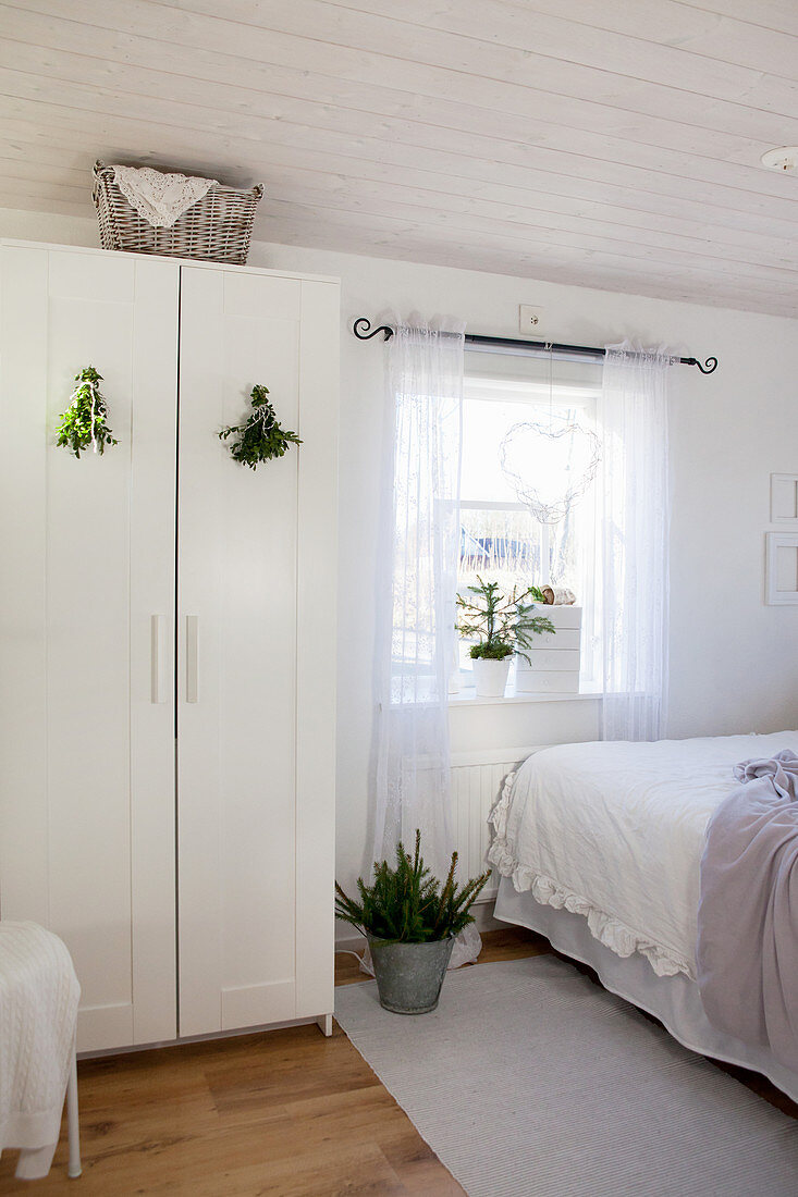 Green posies hung on wardrobe doors in white bedroom