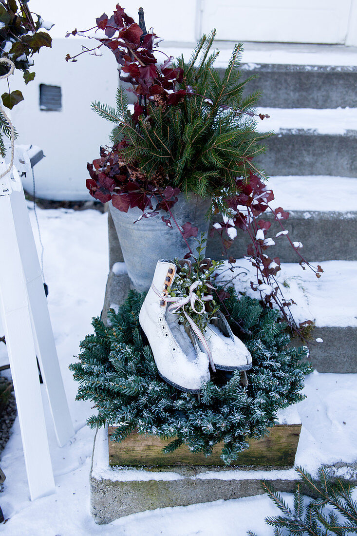 Ice skates on wreath and bucket of branches on steps