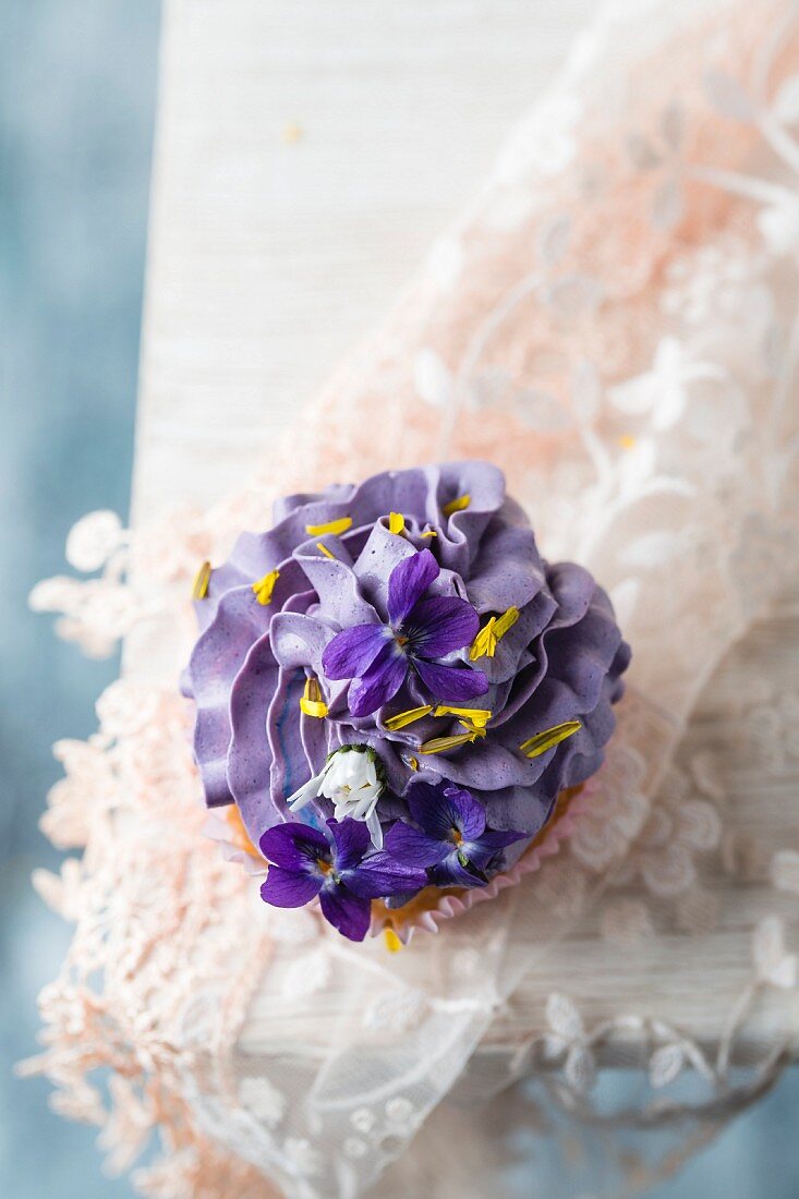 Cupcake mit Veilchen, Gänseblümchen und Löwenzahnblütenblättern