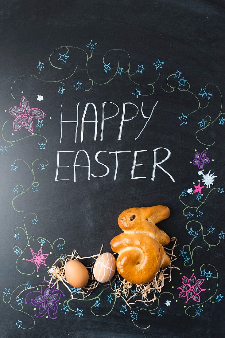 Easter eggs and a bunny (shaped yeast bread) on a chalkboard