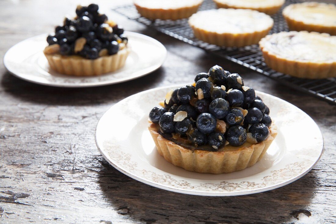 Blueberry and vanilla tartlets on plates and a cooling rack