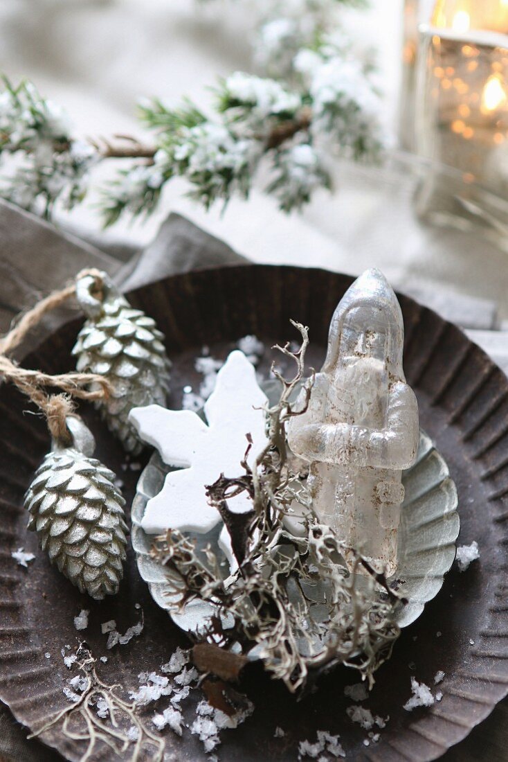 Christmas arrangement of antique glass Father Christmas and silver pine cones in tart tin