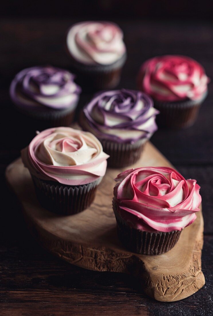 Süsse Rosen-Cupcakes auf Holzbrett