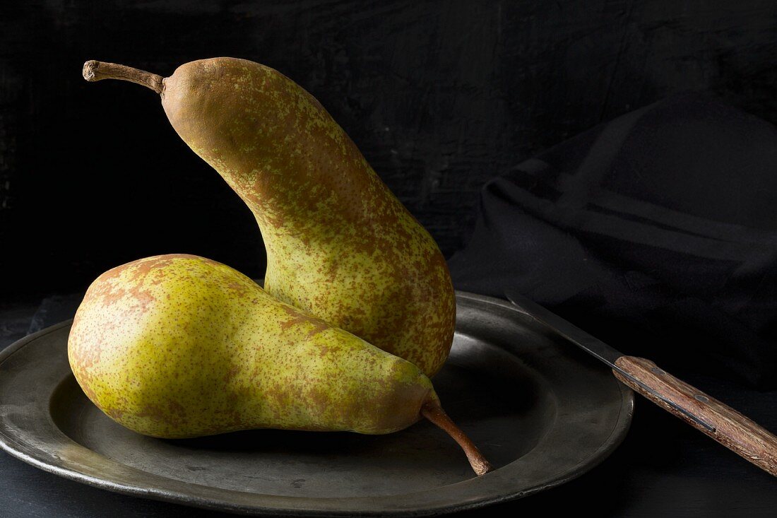 Two Abate Fetel pears on an old tin plate with a knife