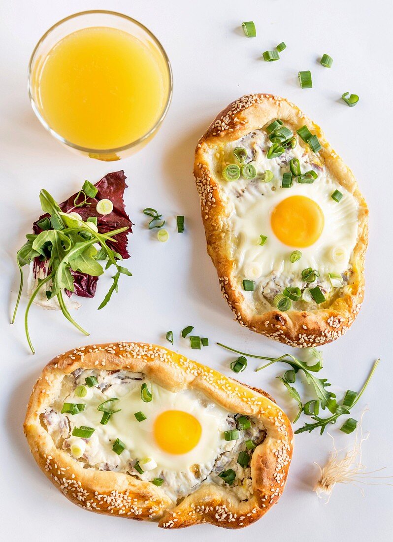 Mini pizzas with fried eggs and a glass of orange juice