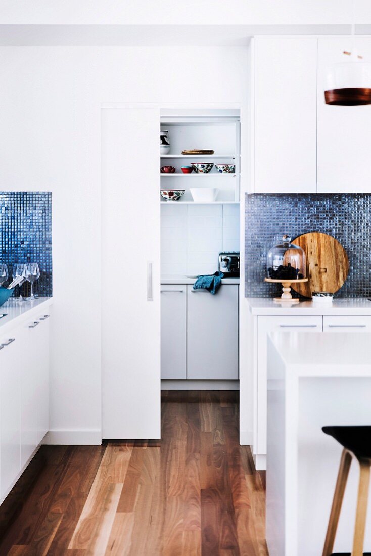 White kitchen with wooden floor and sliding door to the pantry