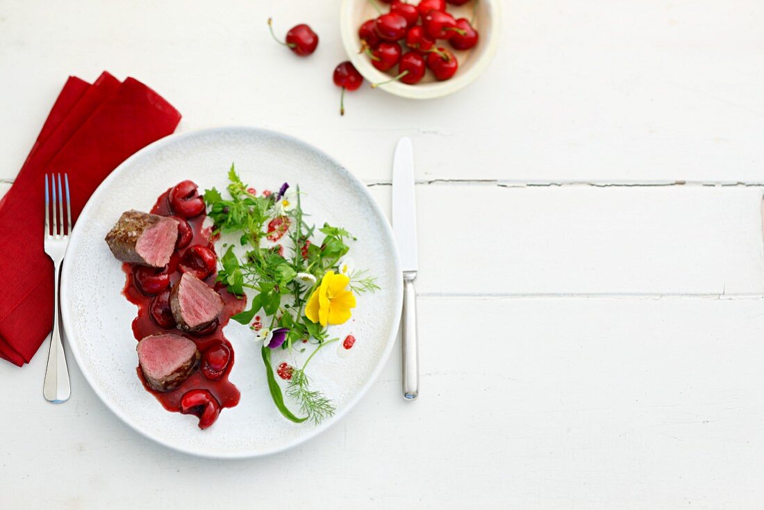 Venison fillets with cherry sauce and a herb salad