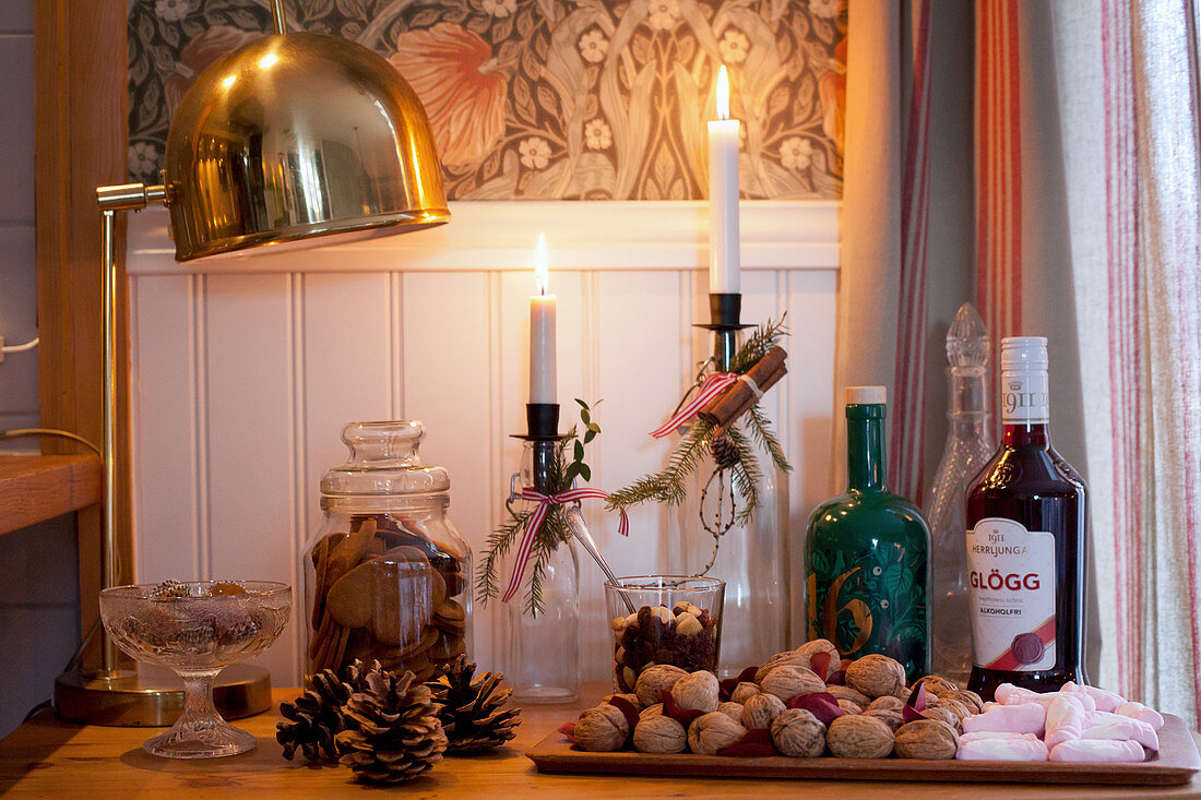 Winter arrangement of candles in bottles, nuts, pine cones and biscuits