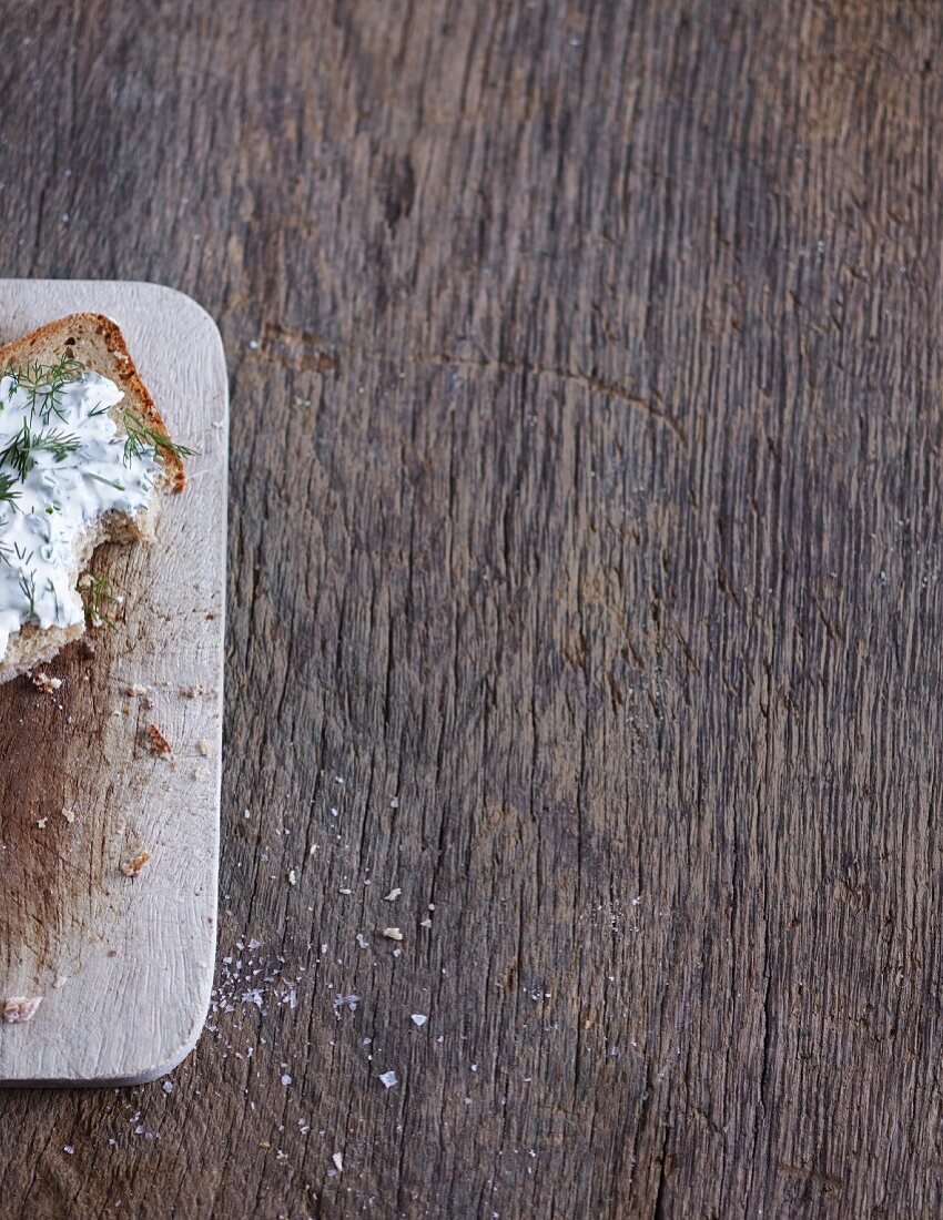 A slice of bread with herb quark on a rustic wooden background