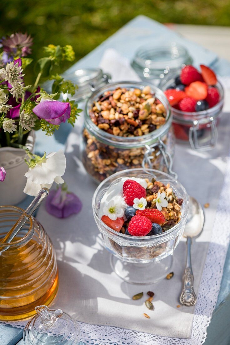 Honig-Granola mit Joghurt und Beeren auf Tisch im Freien